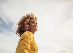 Woman in yellow top with grey clouds in background